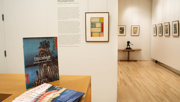 exhibition installation photo including catalog, wall text, and prints