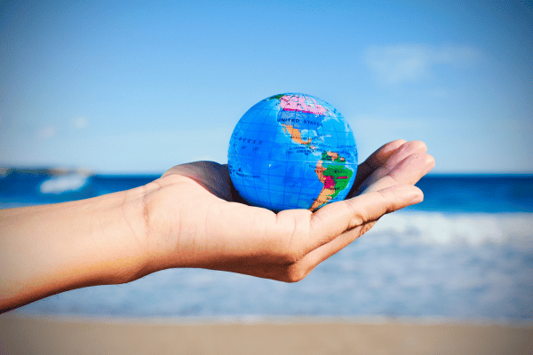 globus in offern hand mit strand im hintergrund bei richtig auswandern dexit online