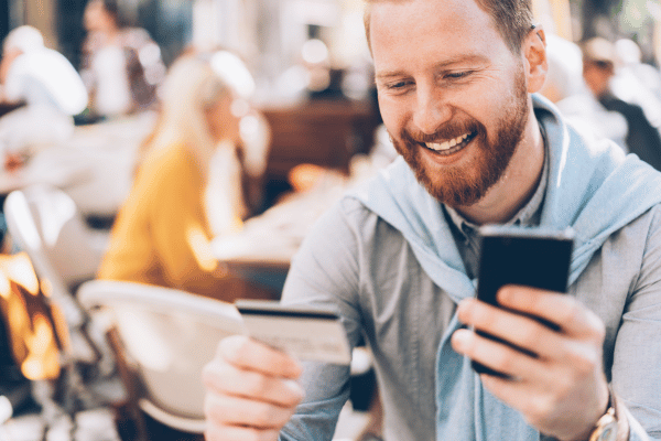 mann testet mobil banking zahlungssysteme  mit handy und kreditkarte in hand