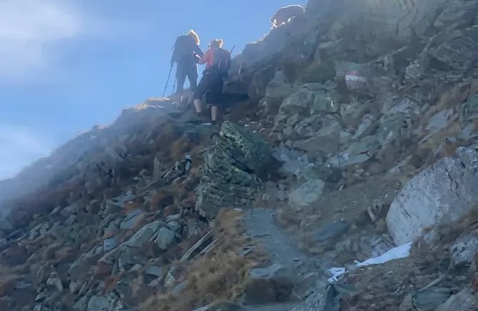 Hikers navigate a steep rocky ridge toward the sun during a sunrise tour in Innsbruck.