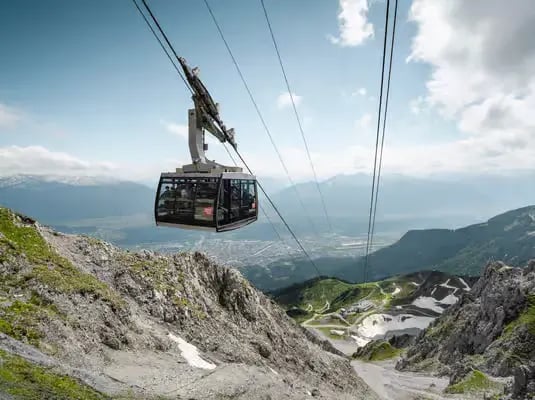 A modern Nordkette cable car cabin ascending the rugged mountain cliffs with a breathtaking view