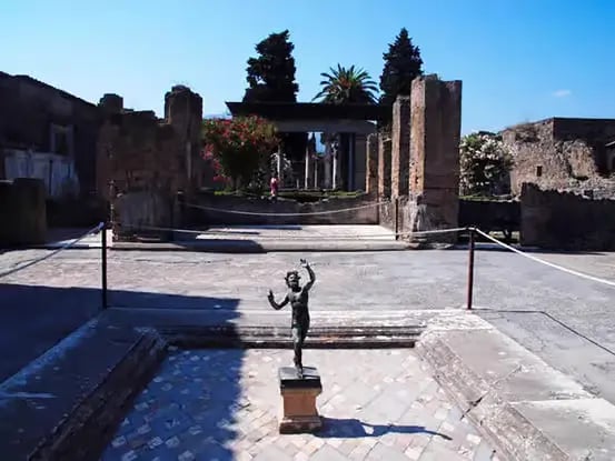 Bronze dancing faun statue in the courtyard of the House of the Faun, Pompeii ruins