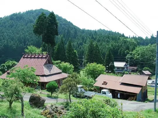 Traditional Japanese farmhouse nestled in a forested mountain valley in rural Kyoto