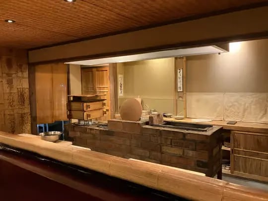 Traditional Japanese restaurant open kitchen with wooden counter and brick hearth, Kyoto