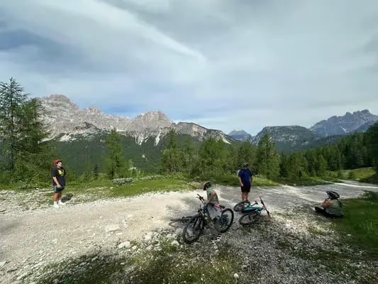 Small group of cyclists resting on mountain gravel trail with Dolomite peaks