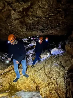 Explorers with helmets and headlamps inside Schwarzenbachloch Cave Bad Goisern