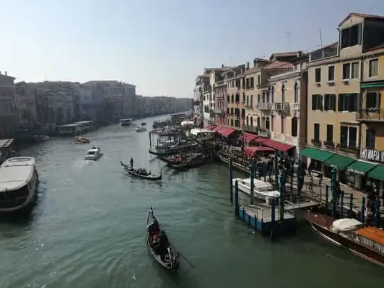 Wide view of the Grand Canal in Venice with gondolas, water buses, and historic buildings.