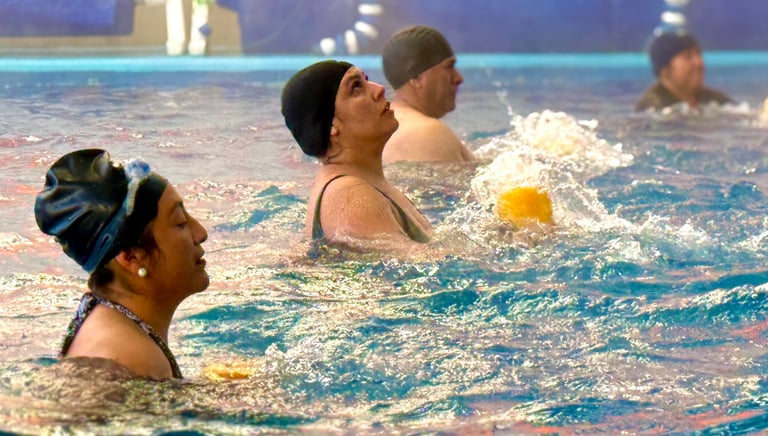 Seniors participating in a water aerobics class at an indoor community swimming pool.
