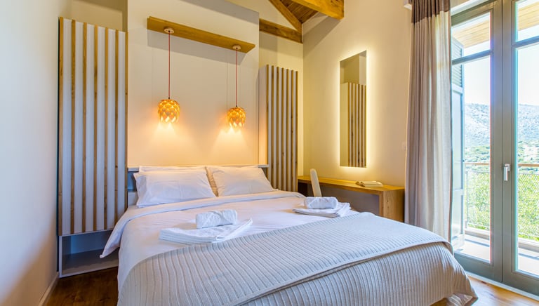 Bright bedroom with double bed and mountain view balcony at Villa Skyphos, Crete