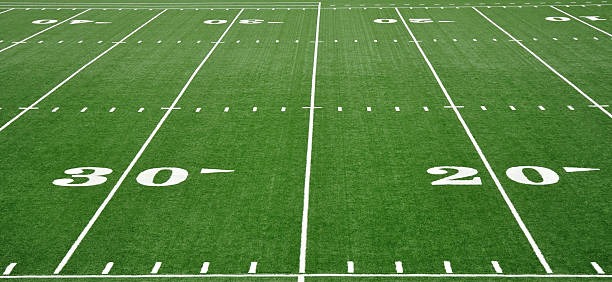 Striping a football field with a trueline grass and turf line marking paint striping machine.