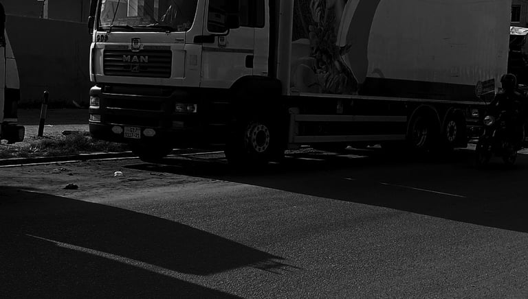 A black and white photograph of a white MAN refrigerated delivery truck with "BRAEM TRUCKS.COM" bran
