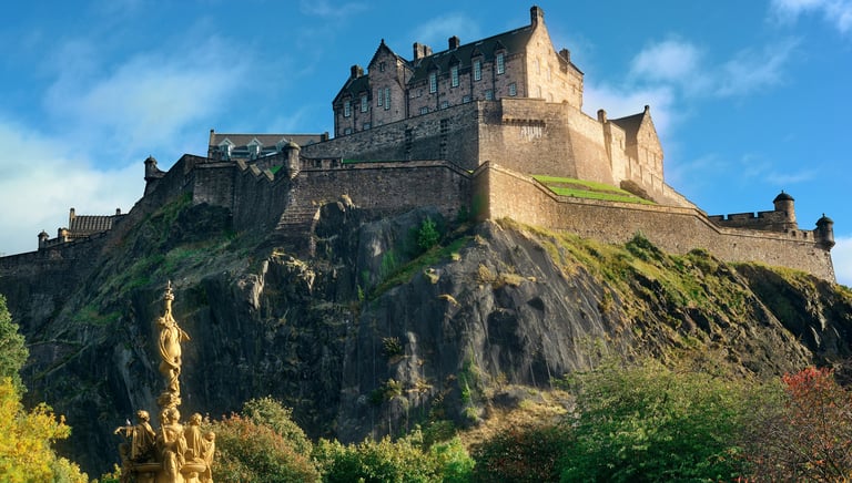 Panoramic view of the historic Edinburgh Castle atop Castle Rock in Scotland under a blue sky.