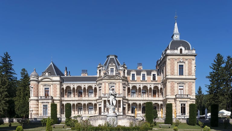 Exterior view of the historic Hermesvilla palace architecture in Vienna with statue and gardens.