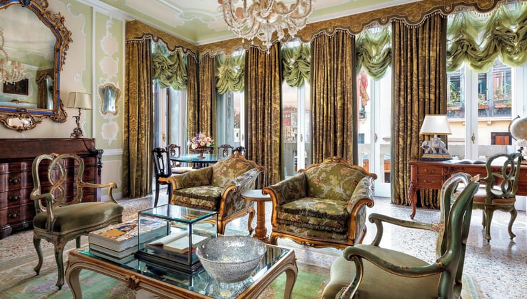 Elegant Venetian luxury suite featuring antique furniture, ornate gold mirrors, and green damask curtains.