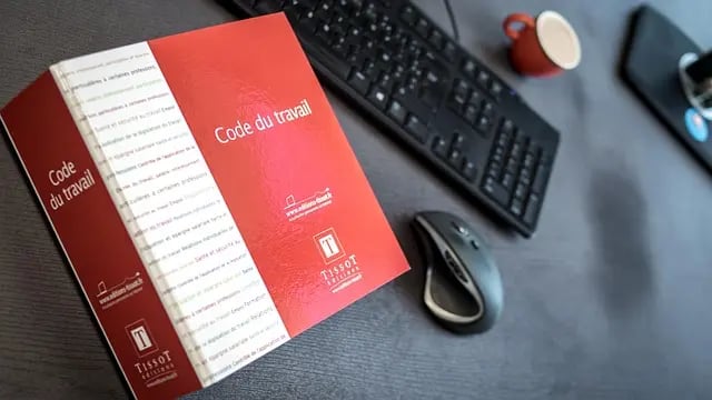 libro rosso con scritto code du travail e tastiera del pc