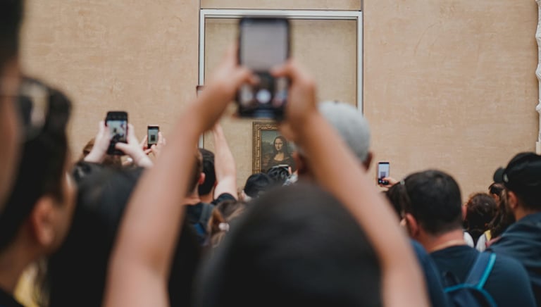 Photo by Tarik on Unsplash מבקרים ממיפים את הסמרטפון מעל ראשיהם כדי לצלם את ציור המונה ליזה .