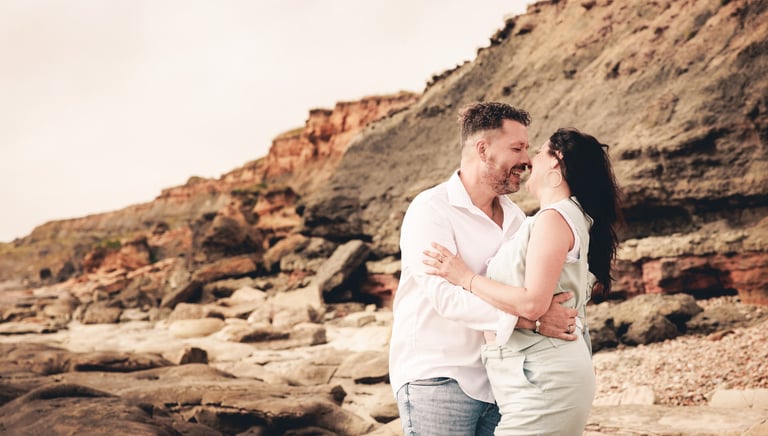 un homme et une femme debout sur des rochers devant une falaise