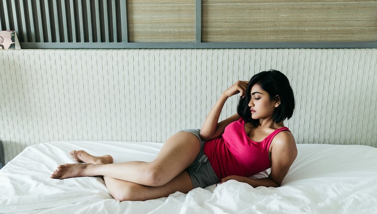 a Sl Ad woman in a pink tank top laying on a bed