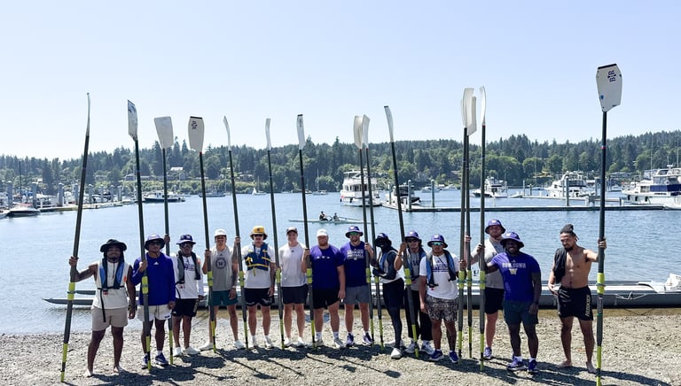 Team standing together holding oars, ready to begin a rowing activity during a team-building retreat