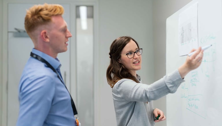 a man and woman standing in front of a white board