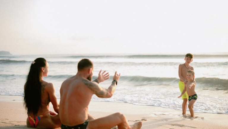 Parents relaxing by the beach while watching their son during a family photography session at Dreamland Beach Bali.