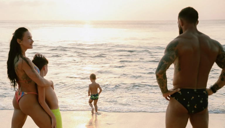 Parents watching their child play near the shoreline during a family photo session at Dreamland Beach Bali.