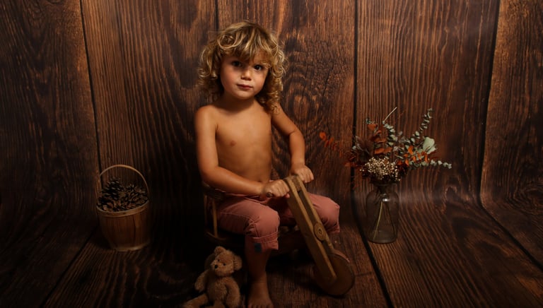 photo d'un petit garçon sur un vieux vélo en bois sur un fond bois 