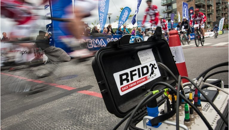 A picture of racers zooming by and RFID chip timing signal collector at a multi-sport event