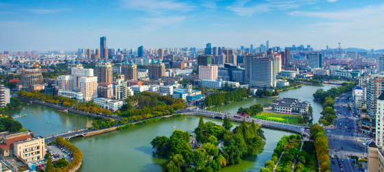 Aerial view of Nantong city skyline with skyscrapers and the Hao River under a clear blue sky.