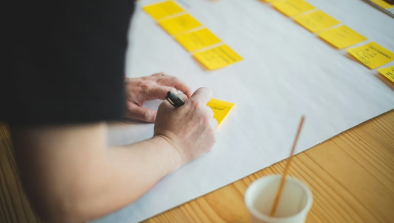 a person writing on sticky note with a pen