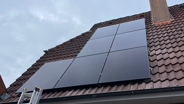 Residential rooftop solar panel installation on a tiled house with an aluminum ladder.