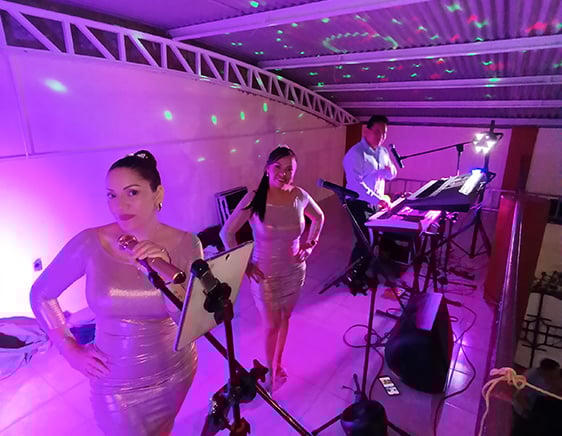 Trío Versátil Army Music actuando en un escenario iluminado en púrpura