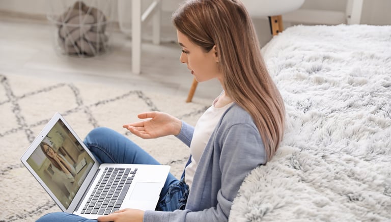 Eine Frau sitzt vor ihrem PC und führt eine online Psychotherapiesitzung durch. 