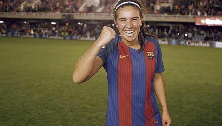 a woman in a soccer uniform is smiling and holding a cell phone