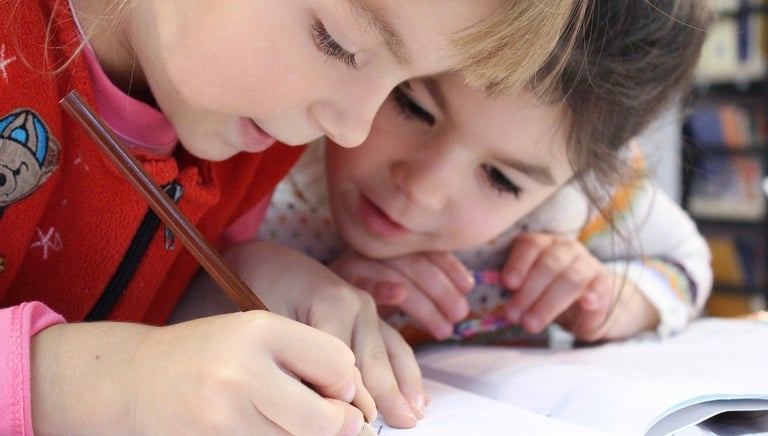 Two young girls working together to complete a workbook