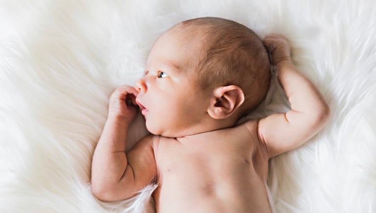 Gorgeous newborn lying awake on bed