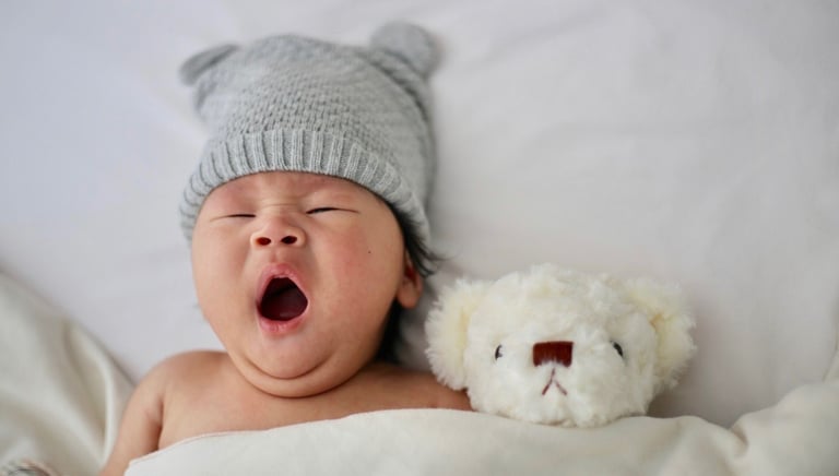 Gorgeous baby yawning with teddy ready for sleep