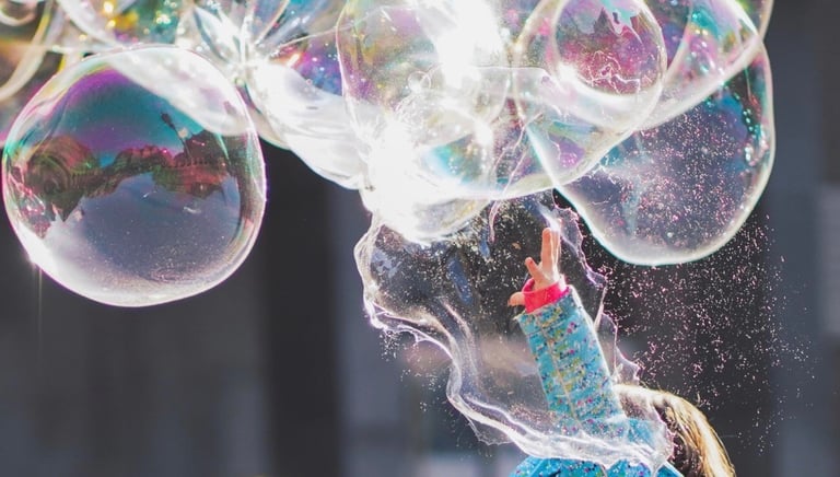 Child trying to catch giant bubbles in a playground