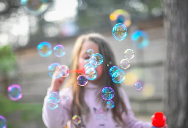 Preschooler blowing bubbles in a park 