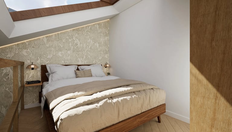 Dormitorio abuhardillado con cama de madera, papel pintado botánico y luz natural.