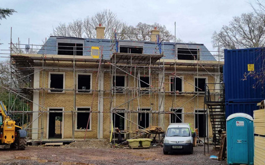 Town houses under construction with scaffolding, a slate tiled roof.