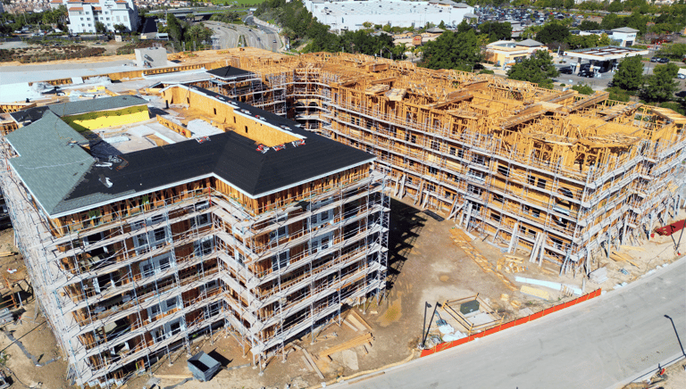 Aerial view of a multi-story wood-frame apartment building construction site with scaffolding.