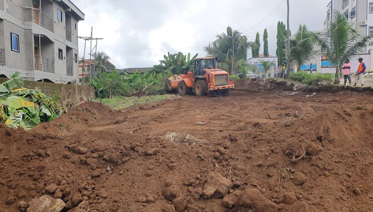 Orange wheel loader excavator clearing soil at a residential construction site for land preparation.