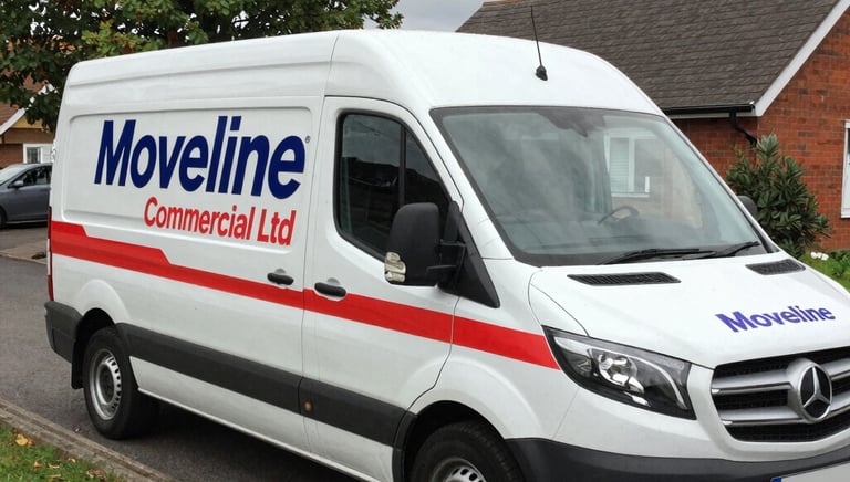 Professional movers loading boxes into a long-wheelbase van in a UK neighborhood