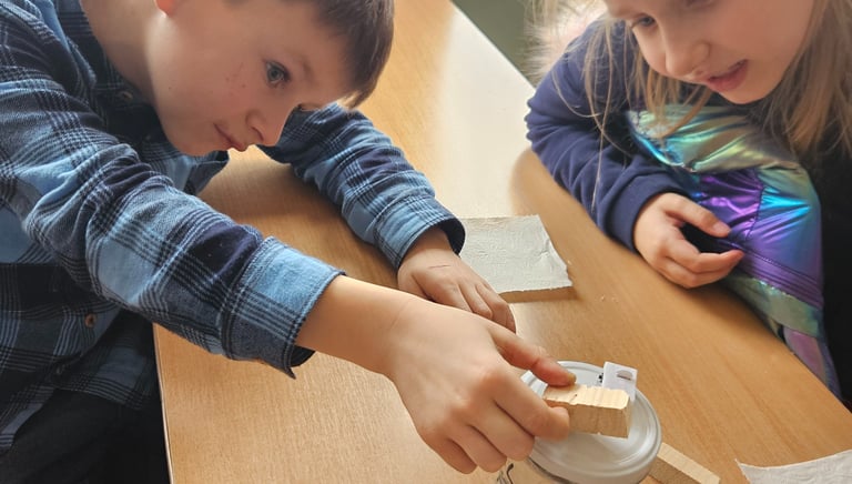 vaikai bendradarbiaudami klijuoja eksperimento detales