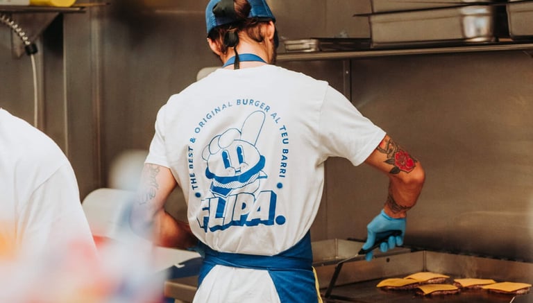 Cuiner de Flipa Burger preparant hamburgueses a la planxa amb l’uniforme de la marca