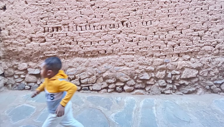 Child running in front of an earthen wall in ksar Amgrou (Zagora) southern Morocco