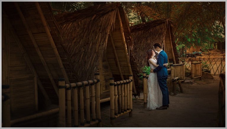 a bride and groom standing in front of bamboo huts