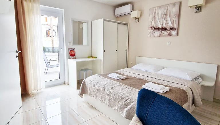 room with bed, chairs, closet, desk and window with balcony