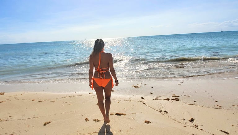 Woman walking into the beautiful caribbean water at Ffryes Beach Antigua